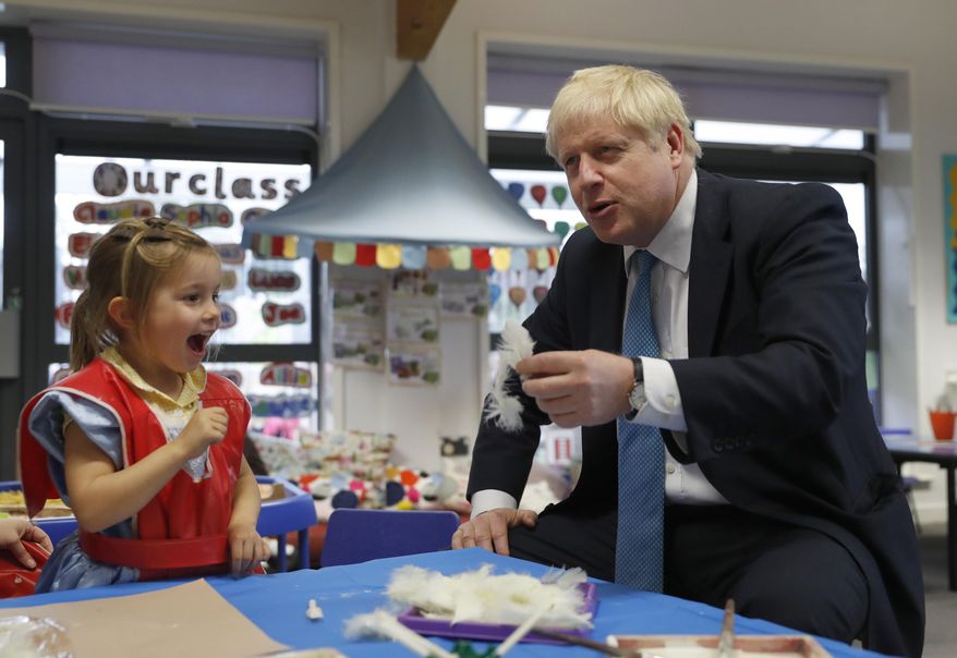 Britain's Prime Minister Boris Johnson gestures as he participates in an art class with Scarlet Fickling aged 4, in at St Mary's and All Saints Primary School in Beaconsfield, England, Friday, Oct. 11, 2019. (AP Photo/Alastair Grant, Pool)