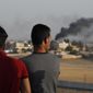 People standing on a rooftop in Akcakale, Sanliurfa province, southeastern Turkey, at the border with Syria, watch as in the background smoke billows from fires caused by Turkish bombardment in Tal Abyad, Syria, Sunday, Oct. 13, 2019.  Turkey&#39;s official Anadolu news agency says Turkey-backed Syrian forces have advanced into the center of a Syrian border town, Tal Abyad, on the fifth day of the Turkey&#39;s military offensive against Kurdish fighters in Syria. (AP Photo/Lefteris Pitarakis)