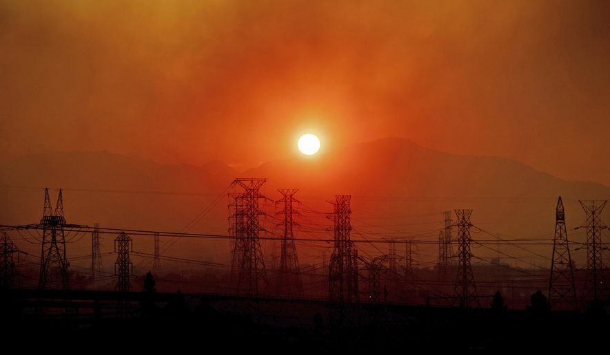 FILE - In this Friday, Oct. 11, 2019, file photo, smoke from a wildfire called the Saddle Ridge Fire hangs above power lines as the sun rises in Newhall, Calif. The destructive fire that broke out on the edge of Los Angeles began beneath a high-voltage transmission tower owned by Southern California Edison, fire officials said Monday, Oct. 14, 2019. (AP Photo/Noah Berger, File)