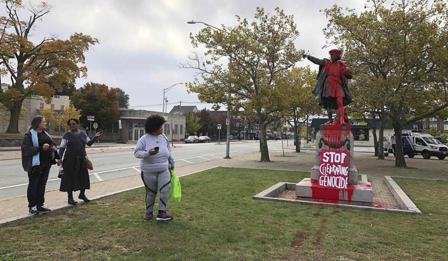 People stop to view red paint covering a statue of Christopher Columbus on Monday, Oct. 14, 2019, in Providence, R.I., after it was vandalized on the day named to honor him as one of the first Europeans to reach the New World. The statue has been the target of vandals on Columbus Day in the past. (AP Photo/Michelle R. Smith)