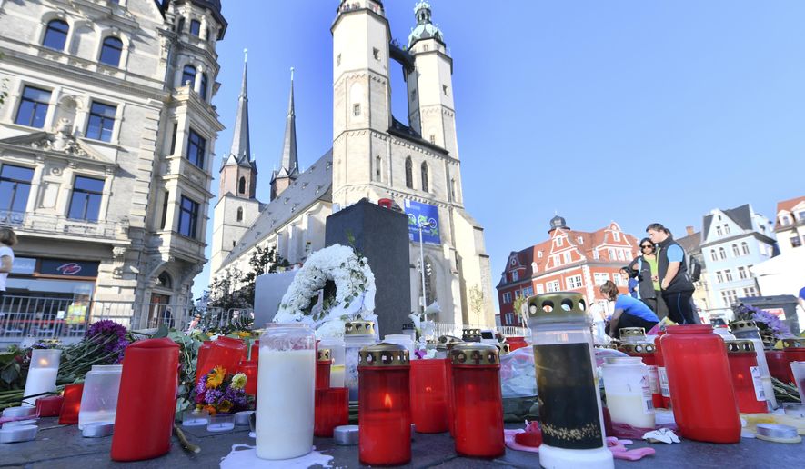 Flowers and candles on the market place remind of the two victims of a right-wing extremist in Halle, Germany, Sunday, Oct. 13, 2019. A heavily armed assailant ranting about Jews tried to force his way into a synagogue in Germany on Yom Kippur, Judaism's holiest day, then shot two people to death nearby in an attack Wednesday that was livestreamed on a popular gaming site. (Hendrik Schmidt/dpa via AP)