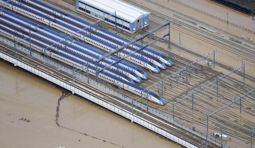 Bullet trains sit at their base as the surrounding land is still flooded following Typhoon Hagibis, in Nagano, central Japan Monday, Oct. 14, 2019. Rescue crews in Japan dug through mudslides and searched near swollen rivers Monday as they looked for those missing from the typhoon that caused serious damage in central and northern Japan. (Kyodo News via AP)