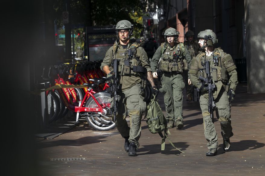 Montgomery County police officers in tactical gear exit a parking garage where a police officer was shot, in downtown Silver Spring, Md., Monday, Oct. 14, 2019. Police in Montgomery County, Maryland, said they were searching for at least one person after an officer was found shot in a parking garage in downtown Silver Spring on Monday. (AP Photo/Jose Luis Magana)