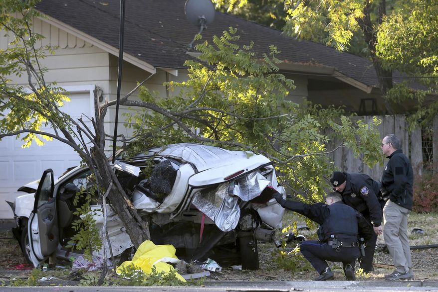 In this Monday, Oct. 14, 2019 photo, police investigate the scene of fatal crash involving a suspected drunken driver in Santa Rosa, Calif. Authorities in Northern California say a 21-year-old man suspected of driving while intoxicated crashed his car against a parked SUV, killing a homeless woman and her dog sleeping inside. (Beth Schlanker/The Press Democrat via AP)