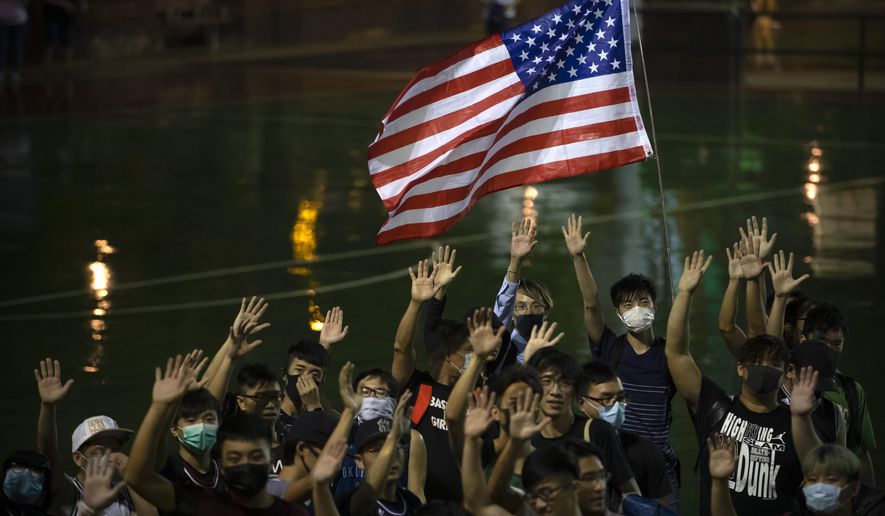 A demonstrator holds a U.S. flag during a rally at the Southorn Playground in Hong Kong, Tuesday, Oct. 15, 2019. Protesters in Hong Kong have thrown basketballs at a photo of LeBron James and chanted their anger about comments the Los Angeles Lakers star made about free speech during a rally in support of NBA commissioner Adam Silver and Houston Rockets general manager Daryl Morey, whose tweet in support of the Hong Kong protests touched off a firestorm of controversy in China. (AP Photo/Mark Schiefelbein)