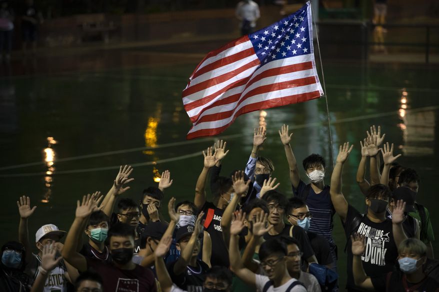 A demonstrator holds a U.S. flag during a rally at the Southorn Playground in Hong Kong, Tuesday, Oct. 15, 2019. Protesters in Hong Kong have thrown basketballs at a photo of LeBron James and chanted their anger about comments the Los Angeles Lakers star made about free speech during a rally in support of NBA commissioner Adam Silver and Houston Rockets general manager Daryl Morey, whose tweet in support of the Hong Kong protests touched off a firestorm of controversy in China. (AP Photo/Mark Schiefelbein)