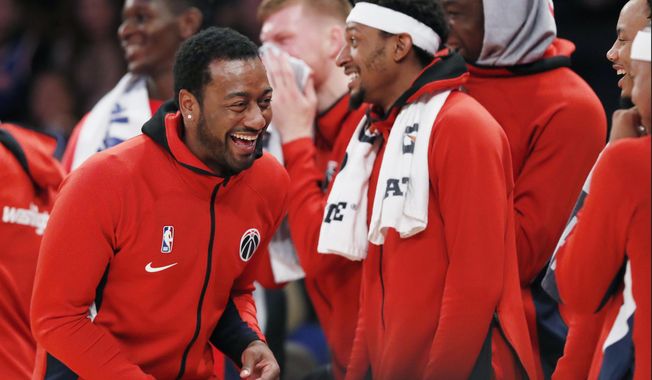 Washington Wizards guard John Wall, left, who is recovering from an Achilles injury, laughs as he watches from the bench with teammates during the waning moments of the team&#x27;s preseason NBA basketball game against the New York Knicks in New York, Friday, Oct. 11, 2019. (AP Photo/Kathy Willens)
