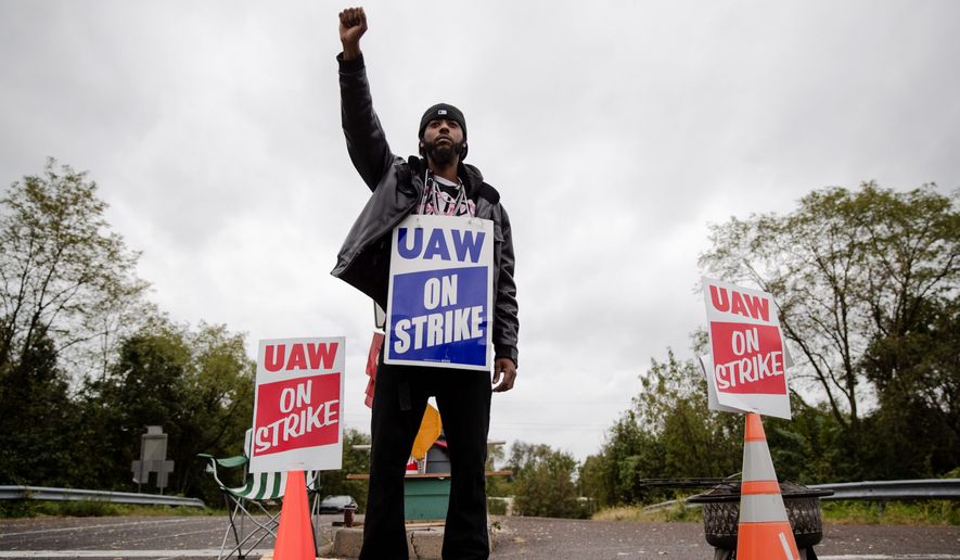 General Motors employee, and others are expected to continue picketing outside the GM Fabrication Division through Friday as bargainers for General Motors and the United Auto Workers iron out details of a tentative contract. (Associated Press)