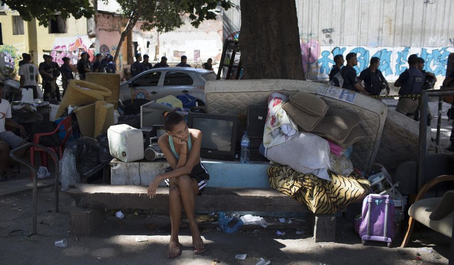 FILE - In this April 27, 2018 file photo, a woman sits next to her belongings during an eviction of squatters at the Mangueira slum of Rio de Janeiro, Brazil. Brazil’s income inequality in 2018 has reached its highest level since the start of the national statistics’ series in 2012, reflecting an economic downturn that’s taken an outsized toll on the poor. Data from the national statistics agency released Wednesday, Oct. 16, 2019. (AP Photo/Leo Correa, File)