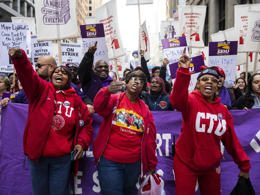 In this Oct. 14, 2019, file photo, members of the Chicago Teachers Union and SEIU Local 73 march through the Loop after a rally, three days before the unions could walk off the job on strike. (Ashlee Rezin Garcia/Chicago Sun-Times via AP) ** FILE **