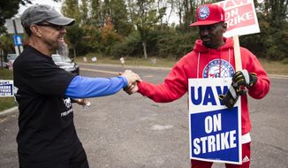 Picketing United Auto Workers Richard Rivera, left, and Will Myatt react to news of a tentative contract agreement with General Motors, in Langhorne, Pa., Wednesday, Oct. 16, 2019. Bargainers for General Motors and the United Auto Workers reached a tentative contract deal on Wednesday that could end a monthlong strike that brought the company&#39;s U.S. factories to a standstill. (AP Photo/Matt Rourke)