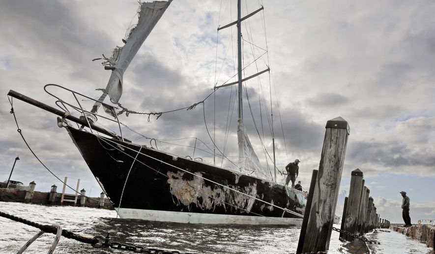 Concerned residents try to stabilize the 55-foot sailboat Fearless, which was damaged after it washed into a wharf in Mattapoisett harbor due to strong overnight winds, Thursday morning, Oct. 17, 2019, in Mattapoisett, Mass. ( Peter Pereira/Standard Times via AP)