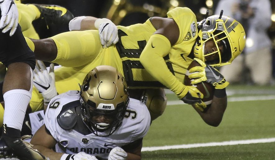Oregon's Jaylon Redd, top, dives into the end zone for a touchdown over Colorado's Aaron Maddox during the second quarter of an NCAA college football game Friday, Oct. 11, 2019, in Eugene, Ore. (AP Photo/Chris Pietsch)