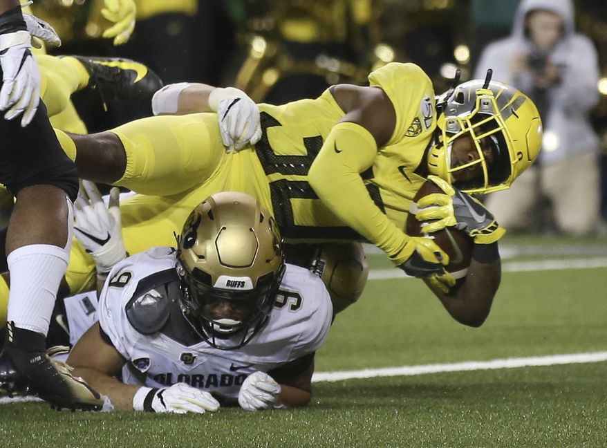 Oregon's Jaylon Redd, top, dives into the end zone for a touchdown over Colorado's Aaron Maddox during the second quarter of an NCAA college football game Friday, Oct. 11, 2019, in Eugene, Ore. (AP Photo/Chris Pietsch)