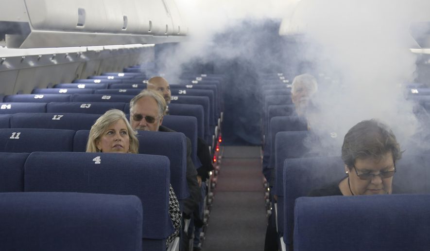 FAA employees participate in a demonstration of an airline cabin filling with smoke, in a simulator at the FAA Civil Aerospace Medical Institute in the Mike Monroney Aeronautical Center, Thursday, Oct. 17, 2019, in Oklahoma City. Federal researchers, using 720 volunteers in Oklahoma City, will test whether smaller seats and crowded rows slow down airline emergency evacuations. (AP Photo/Sue Ogrocki)