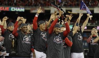 Washington Nationals manager Dave Martinez raises the NLCS trophy after Game 4 of the baseball National League Championship Series against the St. Louis Cardinals Tuesday, Oct. 15, 2019, in Washington. The Nationals won 7-4 to win the series 4-0. (AP Photo/Jeff Roberson)