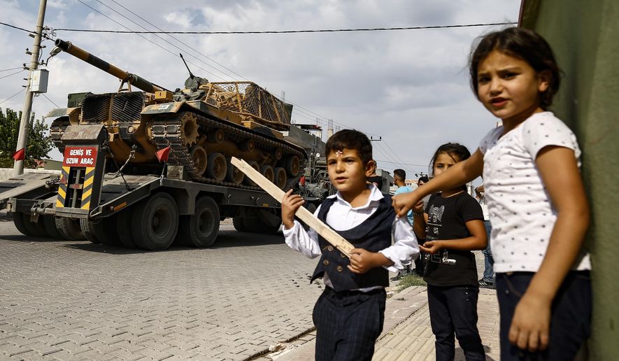 Children watch as army tanks are transported on trucks in the outskirts of the town of Akcakale, in Sanliurfa province, southeastern Turkey, at he border of Syria, Thursday, Oct. 17, 2019. U.S. Vice President Mike Pence, heading a delegation that includes Secretary of State Mike Pompeo and White House national security adviser Robert O'Brien, arrived in Turkey on Thursday, a day after Trump dismissed the very crisis he sent his aides on an emergency mission to douse.(AP Photo/Emrah Gurel)
