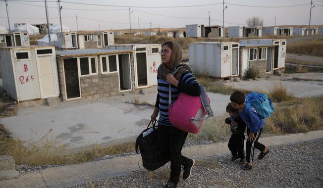 FILE - In this Oct. 17, 2019 file photo, Salwa Hanna with her children, who are newly displaced by the Turkish military operation in northeastern Syria, carry their belongings after they arrive at the Bardarash refugee camp, north of Mosul, Iraq,   For months, every time Turkey threatened to invade northern Syria, Salwa Hanna told her husband they should take their children and flee from the border town of Kobani. And every time, he told her not to worry, because the Americans were there. Now the Christian family is among an estimated 160,000 Syrians who have fled Turkey’s offensive, which began last week after President Donald Trump announced he would move U.S. forces out of the way, abandoning their Kurdish allies.  (AP Photo/Hussein Malla)