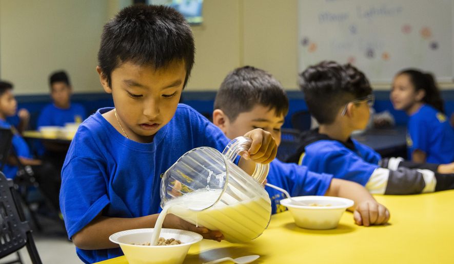 A student pours milk on his cereal as Mayor Lori Lightfoot passes out breakfast to Chicago Public Schools students at a contingency site, Gads Hill Center Friday, Oct. 18, 2019. Striking Chicago teachers have returned to the picket lines for a second day as union and city bargainers try to hammer out a contract in the nation's third-largest school district. (Ashlee Rezin Garcia /Chicago Sun-Times via AP)