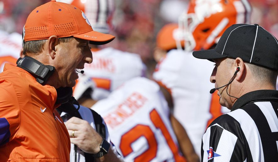 Clemson head coach Dabo Swinney, left, argues with a game official during the first half of an NCAA college football game against Louisville in Louisville, Ky., Saturday, Oct. 19, 2019. (AP Photo/Timothy D. Easley)
