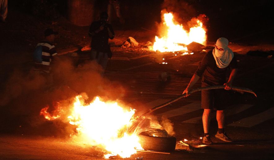 Demonstrators set up burning barricades to block a street during a protest demanding the resignation of President Juan Orlando Hernandez, in Tegucigalpa, Honduras, late Friday, Oct. 18, 2019. The protests come after Tony Hernandez, the brother of President Juan Orlando Hernandez, was convicted in a massive drug conspiracy, that prosecutors of the New York federal court say was protected by the Central American country&#39;s government. (AP Photo/Elmer Martinez)