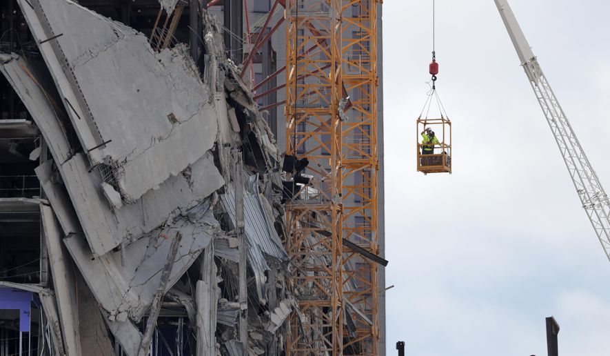 Workers are raised in a crane bucket to prepare two unstable cranes for implosion at the collapse site of the Hard Rock Hotel, which underwent a partial, major collapse while under construction last Sat., Oct., 12, in New Orleans, Saturday, Oct. 19, 2019. (AP Photo/Gerald Herbert)