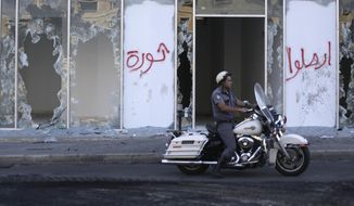 A motorcycle police officer passes by broken glass doors of a shop in the aftermath of a protest against the Lebanese government in Beirut, Lebanon, Saturday, Oct. 19, 2019. The blaze of protests was unleashed a day earlier when the government announced a slate of new proposed taxes, including a $6 monthly fee for using Whatsapp voice calls. Arabic on the wall reads &amp;quot;Revolution, left, Leave.&amp;quot; (AP Photo/Hassan Ammar)