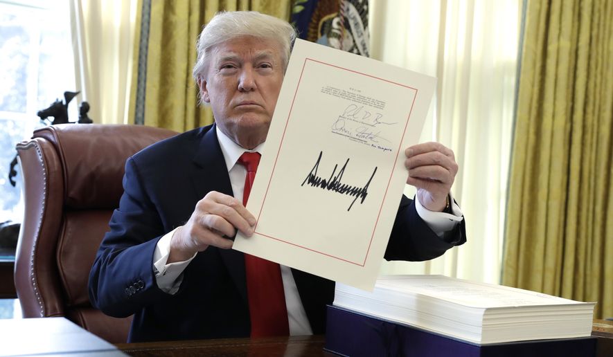 In this Dec. 22, 2017, file photo, President Donald Trump displays the $1.5 trillion tax overhaul package he signed in the Oval Office of the White House in Washington. Trump is now three for three. Each year of his presidency, he has issued more executive orders than did former President Barack Obama during the same time-span. (AP Photo/Evan Vucci, File)