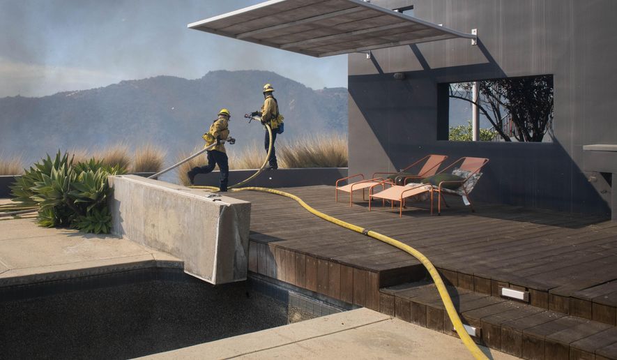 Firefighters protect a home from the flames of a wildfire in the Pacific Palisades area of Los Angeles, Monday, Oct. 21, 2019. (AP Photo/Christian Monterrosa)