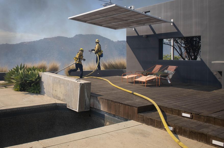 Firefighters protect a home from the flames of a wildfire in the Pacific Palisades area of Los Angeles, Monday, Oct. 21, 2019. (AP Photo/Christian Monterrosa)