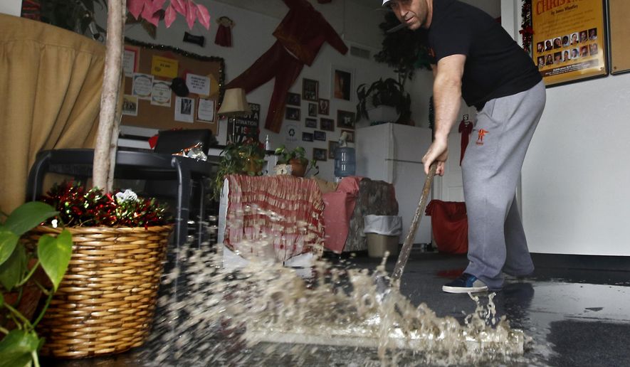 FILE - In this Jan. 5, 2016, file photo, Chris Lene sweeps water out of one of the businesses in the building he owns that was flooded by rainwater in Sacramento, Calif. Climate change is making stronger El Ninos, which change weather worldwide and heat up an already warming planet, according a study in Proceedings of the National Academy of Sciences on Monday, Oct. 21, 2019. (AP Photo/Rich Pedroncelli, File)