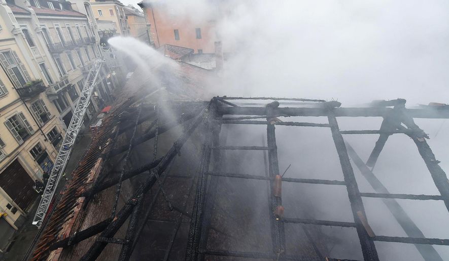 Firefighters put out a fire on the rooftop of the Cavallerizza Reale, in Turin, northern Italy, Monday, Oct. 21, 2019. A big fire broke out on Monday at Turin's Cavallerizza Reale, a historic building in the centre of the northern city which has UNESCO World Heritage status thanks to its special architectural features, no injuries were reported. (Alessandro Di Marco/ANSA via AP)