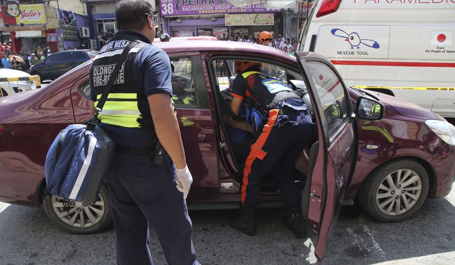 In this Oct. 18, 2019, handout photo provided by the Olongapo Public Information Office, rescue workers check on an Australian named Anthony George inside a car in Olongapo, northern Philippines. Philippine police city director of Olongapo city said they arrested Australian Michael McLaren shortly after the incident for the alleged killing of George and Filipino Mila Bailey inside the car. Another Australian victim, Wayne Bailey, is still recovering at the hospital from gunshot wounds. (Olongapo Public Information Office via AP)