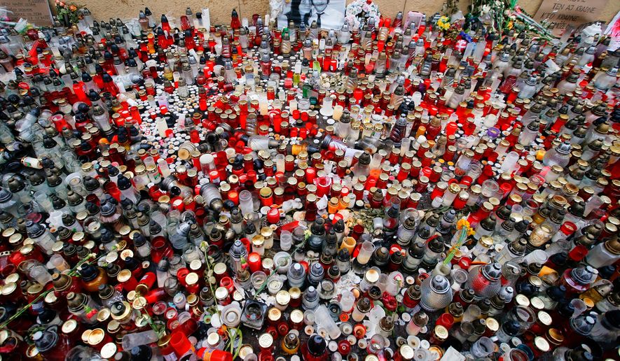 FILE- In this Friday, March 16, 2018 file photo candles are placed in memory of slain journalist Jan Kuciak and his fiancee Martina Kusnirova during a rally in Bratislava, Slovakia. On Monday, Oct. 21, 2019, Slovakia's prosecutors have indicted four suspects for the slaying of an investigative reporter and his fiancee, a case that brought down the Slovak government. (AP Photo/Darko Vojinovic, File)