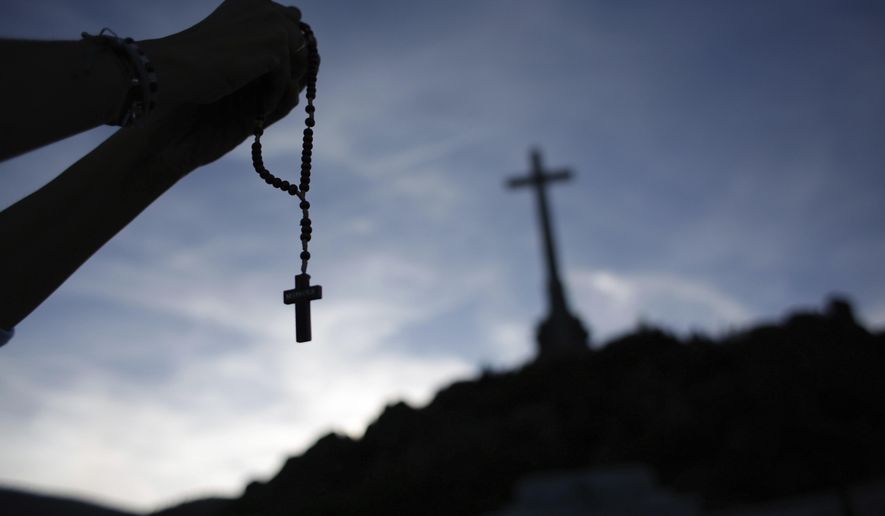 In this Thursday, Oct. 3, 2019, file photo, a worshiper holds a rosary at the Valley of the Fallen mausoleum near El Escorial, outskirts of Madrid, Spain. (AP Photo/Alfonso Ruiz/File)