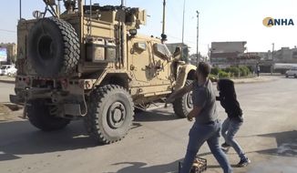 In this frame grab from video provided by Hawar News, ANHA, the Kurdish news agency, residents who are angry over the U.S. withdrawal from Syria hurl potatoes at American military vehicles in the town of Qamishli, northern Syria, Monday, Oct. 21, 2019. Defense Secretary Mark Esper said Monday in Afghanistan that U.S. troops will stay in eastern Turkey to protect Kurdish-held oil fields for at least the coming weeks and that he was discussing options to keep them there. (ANHA via AP)