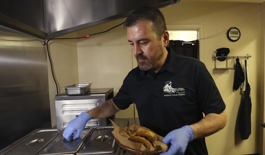 In this Thursday, Oct. 10, 2019 photo, Jose Gamiz, a co-owner at the Mi Vegana Madre restaurant, prepares fresh vegan tacos in Glendale, Ariz. No longer just a few items on a mainstream restaurant’s menu, vegan Mexican food has become a widening industry on its own with Latinos taking control of the kitchen. (AP Photo/Ross D. Franklin)