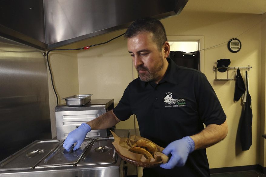 In this Thursday, Oct. 10, 2019 photo, Jose Gamiz, a co-owner at the Mi Vegana Madre restaurant, prepares fresh vegan tacos in Glendale, Ariz. No longer just a few items on a mainstream restaurant’s menu, vegan Mexican food has become a widening industry on its own with Latinos taking control of the kitchen. (AP Photo/Ross D. Franklin)