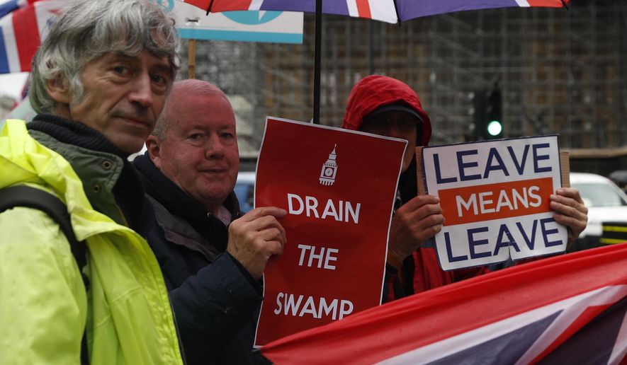 Pro-Brexit protesters hold out their placards and flags as traffic moves past the Houses of Parliament in London, Monday, Oct. 21, 2019.  The European Commission says the fact that British Prime Minister Boris Johnson did not sign a letter requesting a three-month extension of the Brexit deadline has no impact on whether it is valid and that the European Union is considering the request. (AP Photo/Alastair Grant)