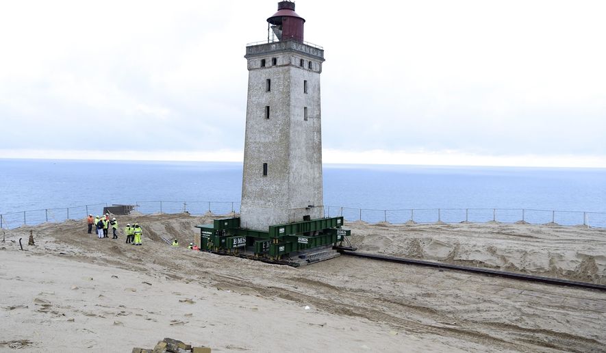 The Rubjerg Knude Lighthouse is being moved in Jutland, Denmark, Tuesday, Oct. 22, 2019. A 120-year-old lighthouse has been put on wheels and rails to attempt to move it some 80 meters (263 feet) away from the North Sea, which has been eroding the coastline of northwestern Denmark. When the 23-meter (76 feet) tall Rubjerg Knude lighthouse was first lit, in 1990, it was roughly 200 meters (656 feet) from the coast; now it is only about 6 meters away. (Henning Bagger/Ritzau Scanpix via AP)