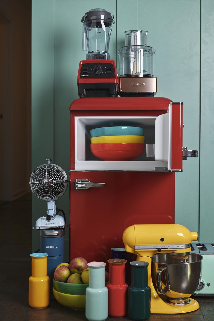 This September 2019 photo provided by Katie Workman shows a variety of kitchen items in different colors, including a red fridge, a yellow stand mixer and some brightly colored bowls and vases, in a New York kitchen. There are a lot of ways to add color to your kitchen. (Cheyenne M. Cohen/Katie Workman via AP)