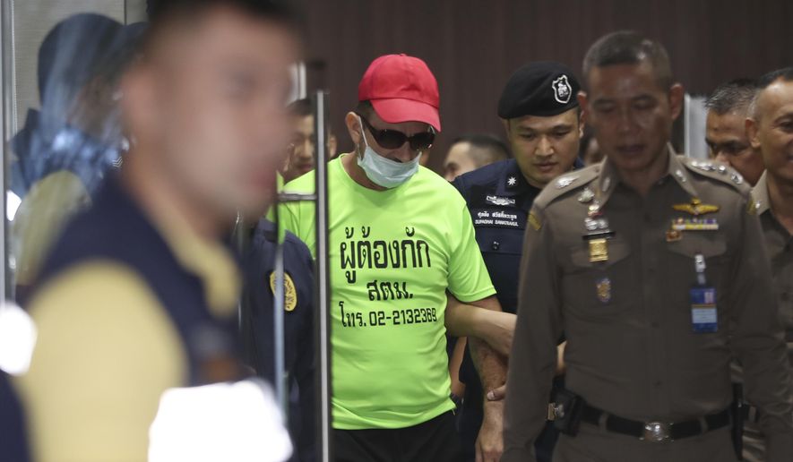 Immigration officers escort Richard Stanislaus, center, at the immigration office in Bangkok, Thailand, Tuesday, Oct. 22, 2019. Police say they are investigating the death of an elderly German woman Margund Schaefer after arresting Stanislaus, also German, for allegedly dumping her body into a canal. (AP Photo/Sakchai Lalit)