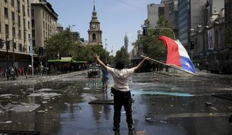 A demonstrator holds a Chilean flag during a protest in Santiago, Chile, Wednesday, Oct. 23, 2019. Rioting, arson attacks and violent clashes wracked Chile as the government raised the death toll to 15 in an upheaval that has almost paralyzed the South American country long seen as the region&#39;s oasis of stability. (AP Photo/Rodrigo Abd)