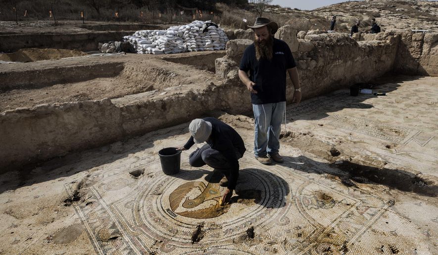 An Israeli archaeologist Binyamin Storchan, right, from the Israel Antiquities Authority, shows a mosaic depicting an eagle in an ancient church that was recently uncovered in Beit Shemesh, near Jerusalem. Wednesday, Oct. 23, 2019. Israeli archaeologists have revealed an elaborately decorated Byzantine church dedicated to an anonymous martyr that was recently uncovered near Jerusalem. The Israel Antiquities Authority showcased some of the finds from the nearly 1,500-year-old structure on Wednesday after three years of excavations. (AP Photo/Tsafrir Abayov)
