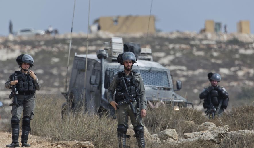 Israeli border police secure a road leading to a newly established Israeli settlers outpost, seen in the background, during clashes with Palestinian protesters in the West Bank village of Tormusayya, northeast of Ramallah, Thursday, Oct. 17. 2019. Palestinian protesters marched toward a newly established Israeli settlers outpost on the outskirts of the Palestinian village of Tormusayya, before clashing with Israeli forces blocking the road leading to the outpost. (AP Photo/Nasser Nasser)