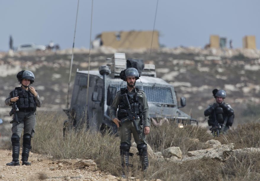 Israeli border police secure a road leading to a newly established Israeli settlers outpost, seen in the background, during clashes with Palestinian protesters in the West Bank village of Tormusayya, northeast of Ramallah, Thursday, Oct. 17. 2019. Palestinian protesters marched toward a newly established Israeli settlers outpost on the outskirts of the Palestinian village of Tormusayya, before clashing with Israeli forces blocking the road leading to the outpost. (AP Photo/Nasser Nasser)