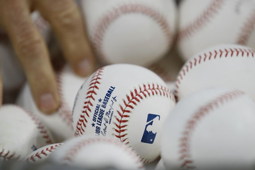 A Washington Nationals player reaches for a ball during batting practice before Game 2 of the baseball World Series against the Houston Astros Wednesday, Oct. 23, 2019, in Houston. (AP Photo/Matt Slocum)