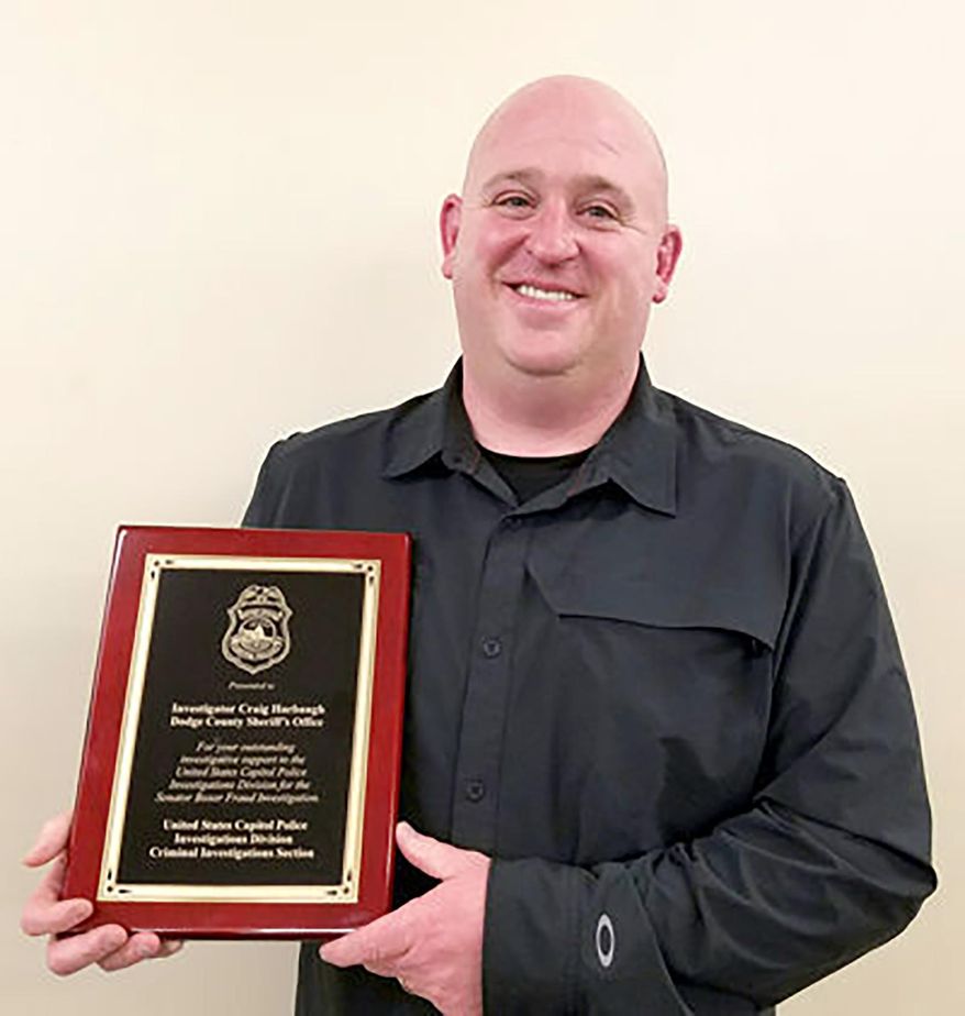 In a Feb 17, 2017 photo, Dodge County Sheriff's Investigator Craig Harbaugh receives recognition from the U.S. Capitol Police for his outstanding investigative support in a fraud investigation. Harbaugh has been charged with fraud in a scheme that authorities say cost his victims nearly $11 million. Federal court records say 44-year-old Craig Harbaugh faces 13 counts of wire fraud and two more of bank fraud for acts committed between October 2014 and October 2019. He pleaded not guilty after an indictment was filed Monday, Oct. 21, 2019. (The Tribune via AP)