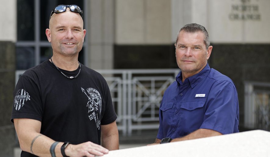 In this Thursday, Sept. 12, 2019, photo, Eric Reynolds, left, and Dave Stull, both police officers, pose for a picture in Orlando, Fla. They recently found out they were half brothers though a DNA test. (AP Photo/John Raoux)