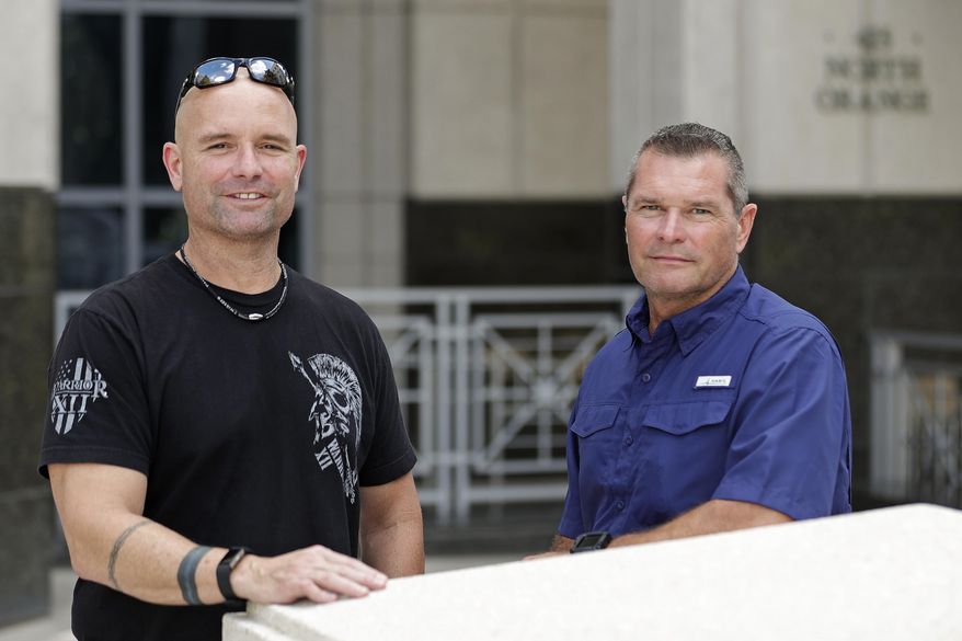 In this Thursday, Sept. 12, 2019, photo, Eric Reynolds, left, and Dave Stull, both police officers, pose for a picture in Orlando, Fla. They recently found out they were half brothers though a DNA test. (AP Photo/John Raoux)